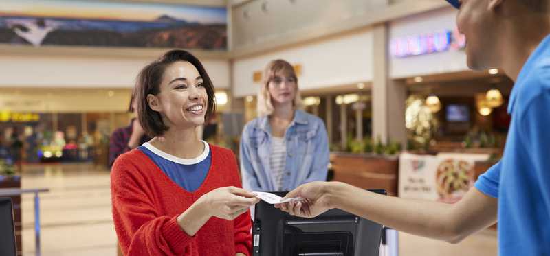 Person handing something to cashier at checkout counter.