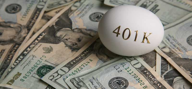 An egg with 401(k) written on it on top of a pile of cash.