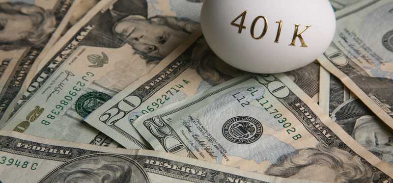An egg with 401(k) written on it on top of a pile of cash.