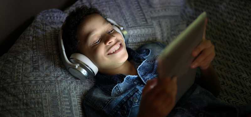 Smiling young boy wearing headphones looking at tablet