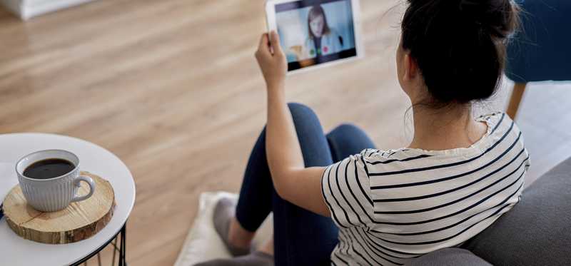 Woman having telehealth session with doctor using tablet.