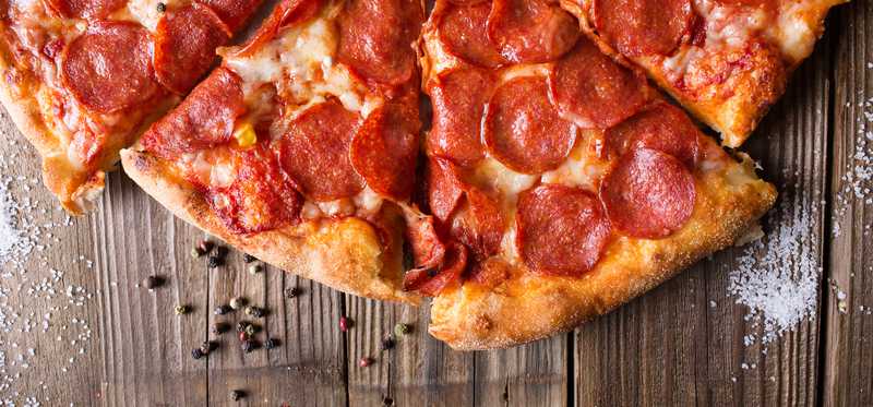 A sliced pizza on a wooden table.