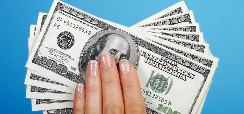 Hand holding fanned out hundred dollar bills.
