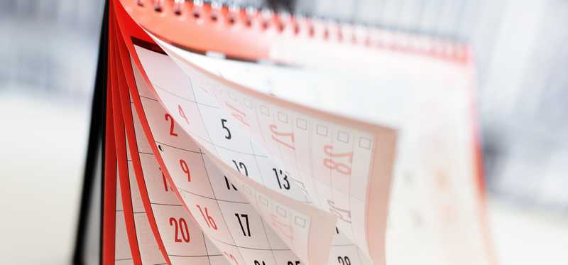 A stand-up monthly desk calendar with fluttering pages.