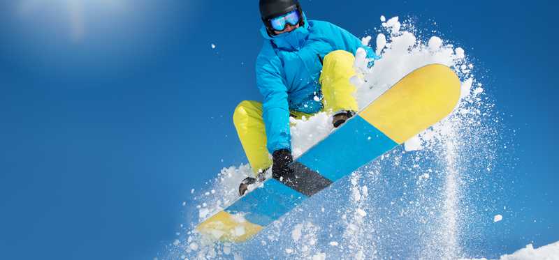A snowboarder does a jump while grabbing his board.
