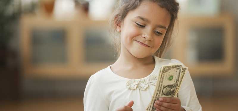 Little girl smiling and holding one dollar bills