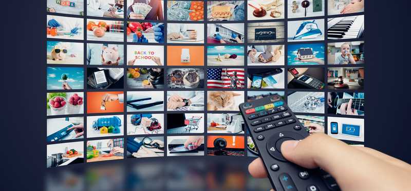 Person holding remote and streaming shows.
