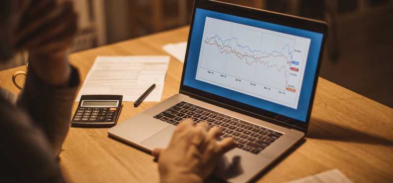 Person tracking stock returns on laptop.