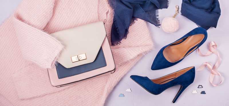 Sweater, purse, scarf, and high heels against lavender backdrop