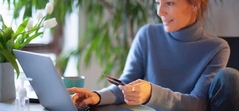 Woman looking at computer and holding credit card