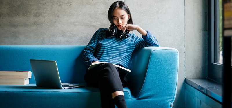 Person sitting on couch and reading a book.