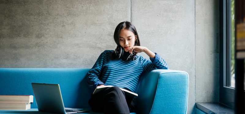 Person sitting on couch and reading a book.