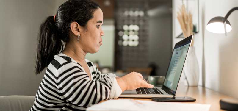 Person sitting at desk and typing on laptop.