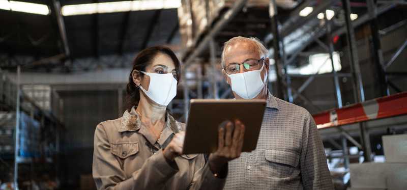 People checking inventory on tablet in storage warehouse.