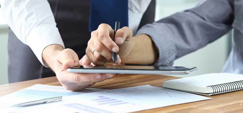 Businessman signing electronic document on a tablet.