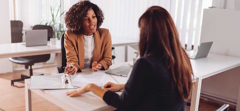 Financial advisor sitting at desk and reviewing documents with client