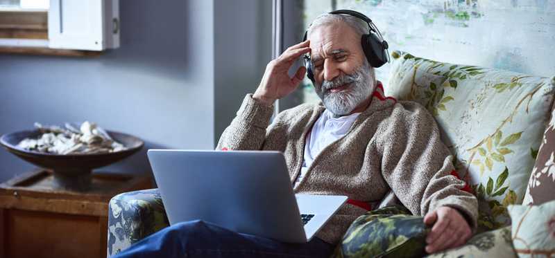 Person wearing headphones and looking at laptop.