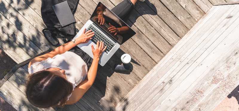 Woman working on laptop on sunny deck