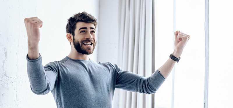 Young man cheering for joy and smiling over good news