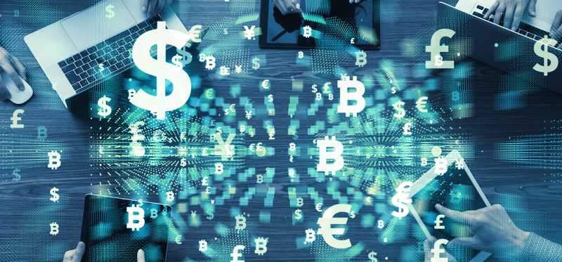 A group of people sitting around a table on electronic devices with symbols in the air around them indicating different currencies.