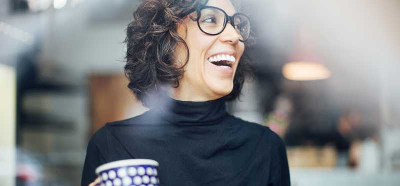 Person holding coffee cup and smiling.