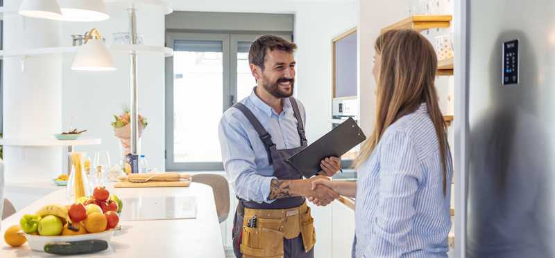 Person shaking hands with a repair technician in a kitchen.