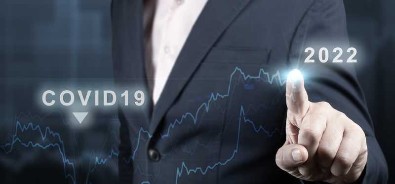 Businessperson pointing to chart economic recovery from COVID-19 to 2022.