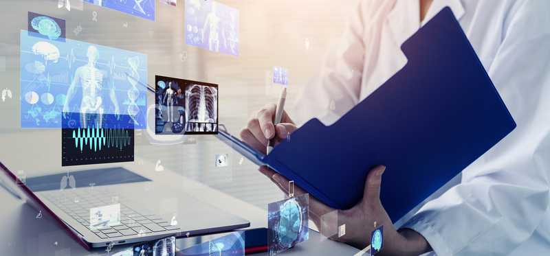 Doctor reviewing documents in folder surrounded by electronically projected images of human body