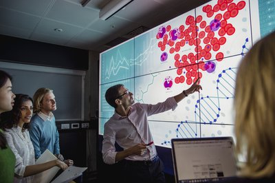 Group of scientists gathered in room watching presentation on DNA blockchain data