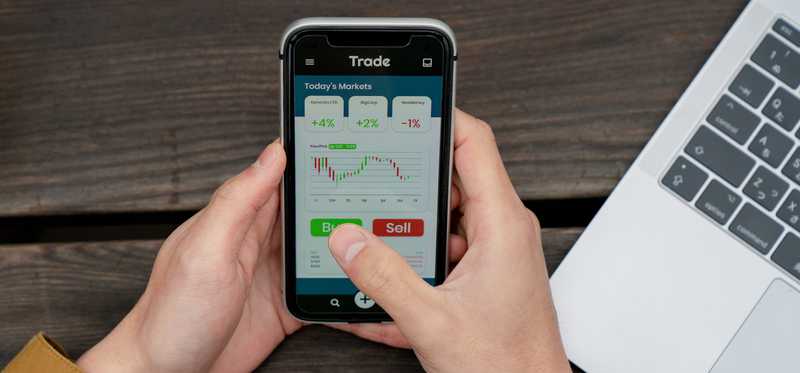 Person using mobile trading app to buy and sell stocks.