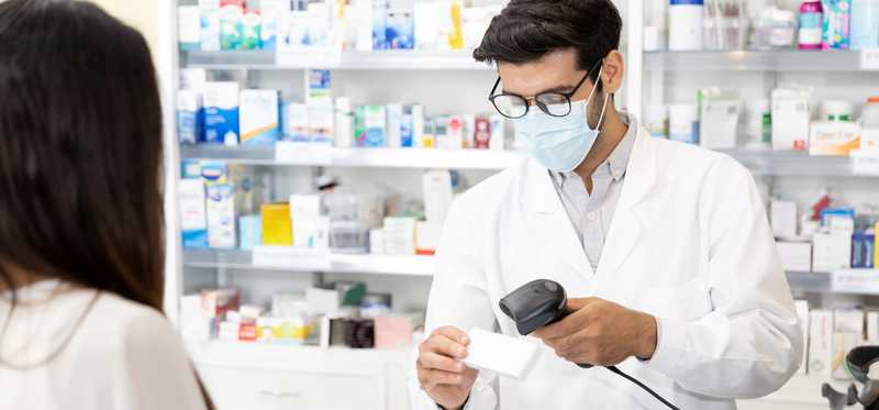 Pharmacist scanning medication bar code for patient at counter