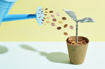Watering can raining pennies on planter filled with coins.