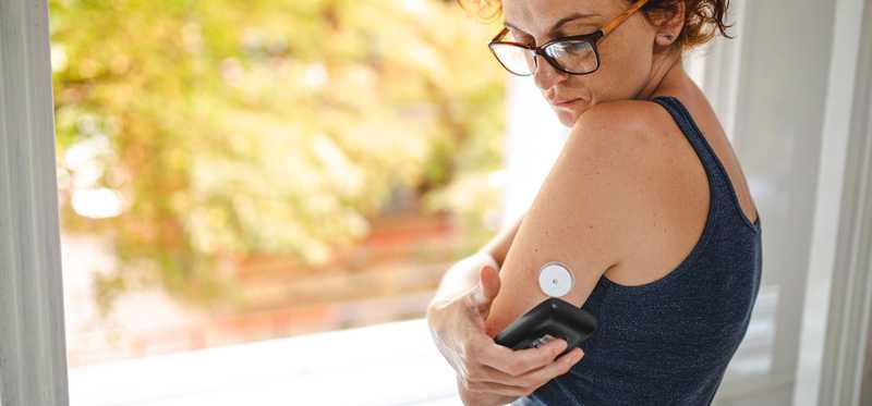 Woman with diabetes checking continuous glucose monitoring device