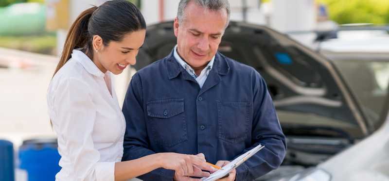 People reviewing paperwork near cars