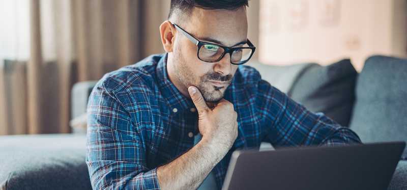 Person looks pensively at laptop screen.