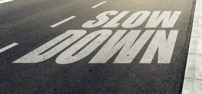 The words Slow Down painted on a road.
