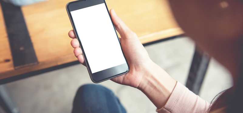 Person holds a smartphone with a blank screen.