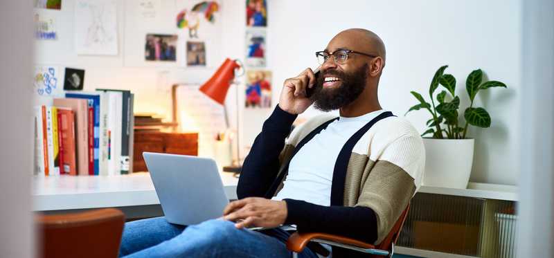 Smiling person talking on phone in office.