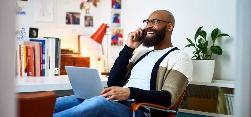 Smiling person talking on phone in office.