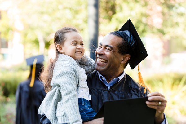 Smiling graduate holding a child.