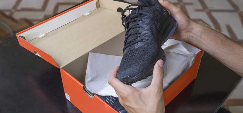 A man takes a sneaker out of an orange box.