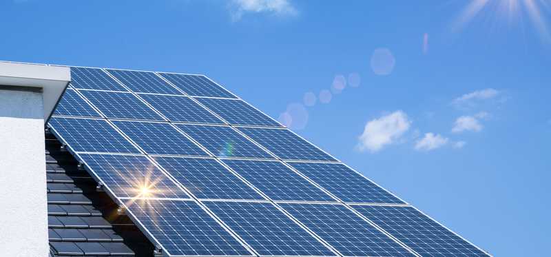 A solar panel on a roof with blue sky background.