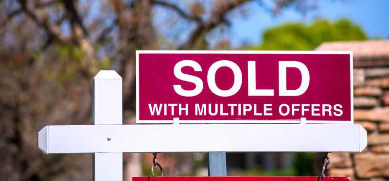 A sign in a yard that says Sold With Multiple Offers.