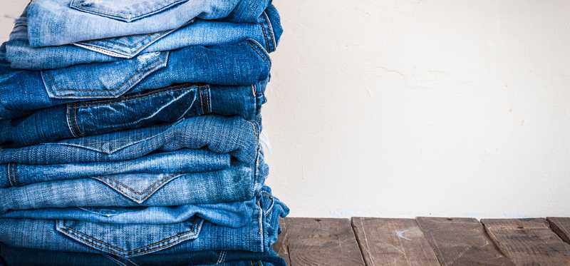 A stack of blue jeans on a wooden table top