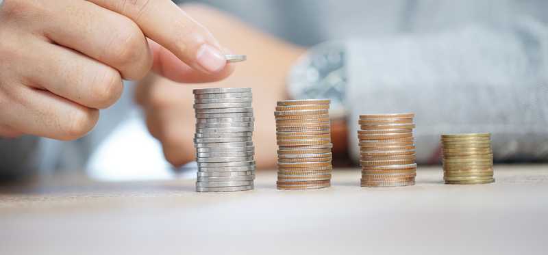 Hand putting nickels and dimes one by one onto stacks of coins.
