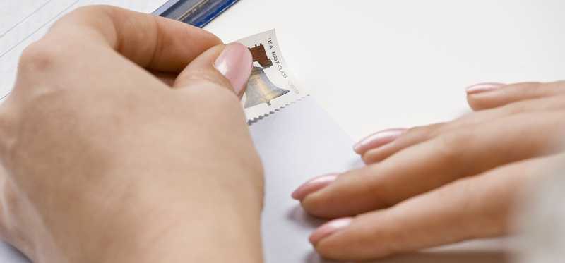 Hand puts a stamp on an envelope.