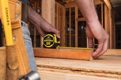 Construction worker using a Stanley Fatmax tape measure on the job.