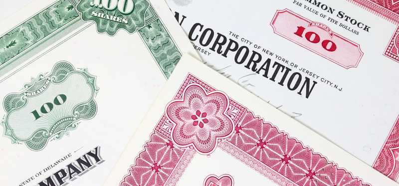 Stock certificates in a messy pile.
