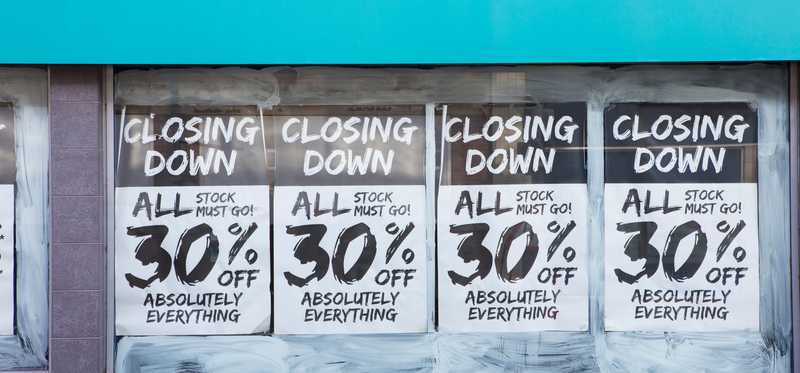 Sale signs in the windows of a store that is closing