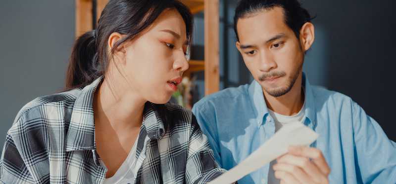 Two stressed people looking at receipt.